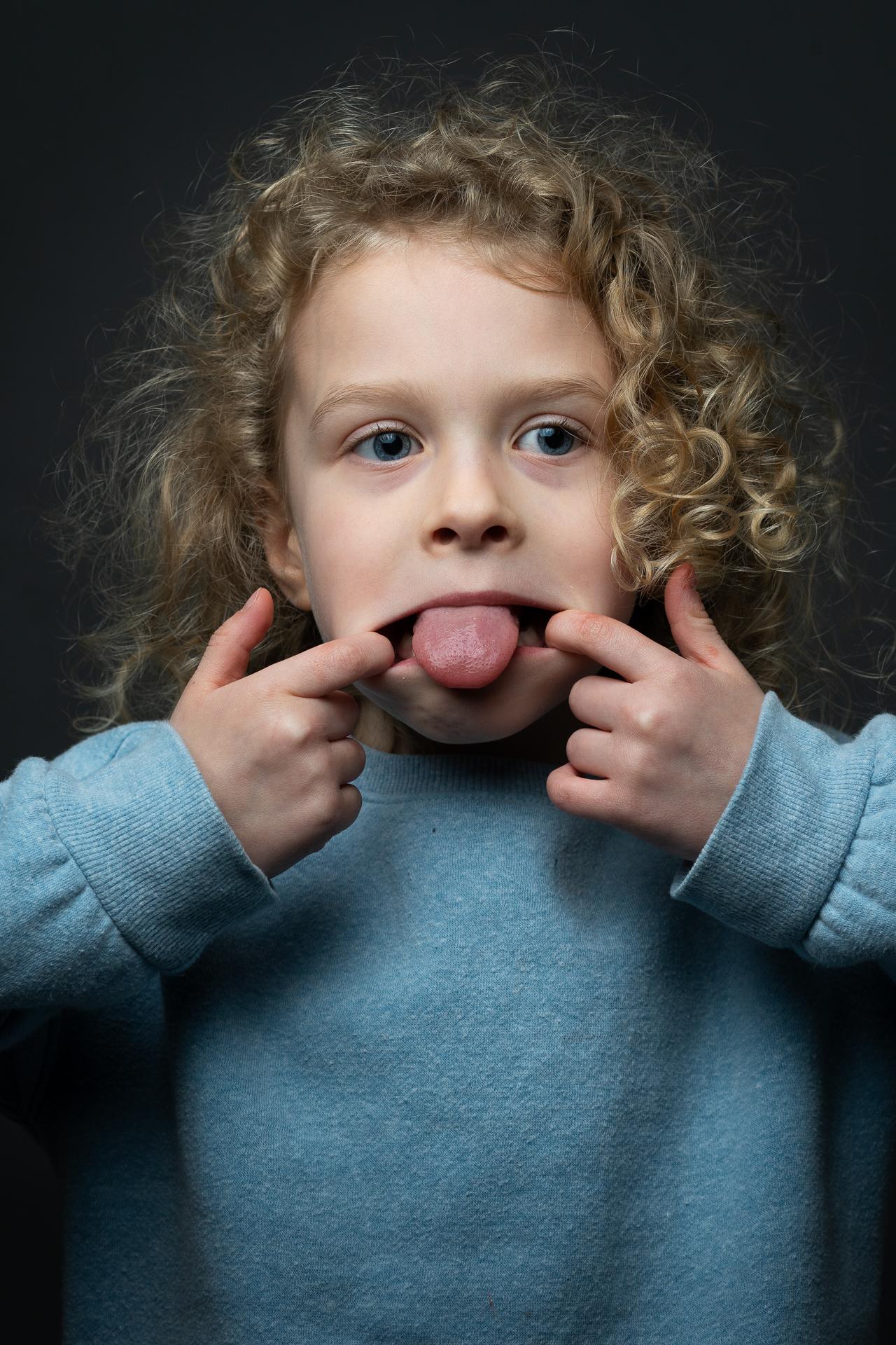 Kiddo holder her fingers to the corners of her mouth, sticking her tongue out