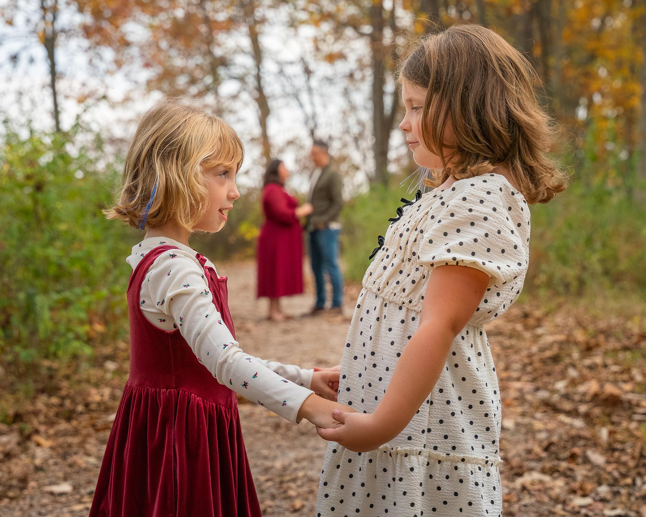 Sisters holding hands with mom and dad in the background